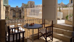 Un balcón con una mesa, sillas y vistas a edificios históricos de piedra.