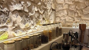 Una cocina con paredes de piedra, una cesta de frutas y una cafetera.