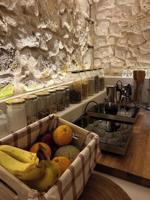 A kitchen with stone walls, a fruit basket, and a coffee machine. - NEW: 400-year-old home bed and breakfast (Ir-rabat(Malta)