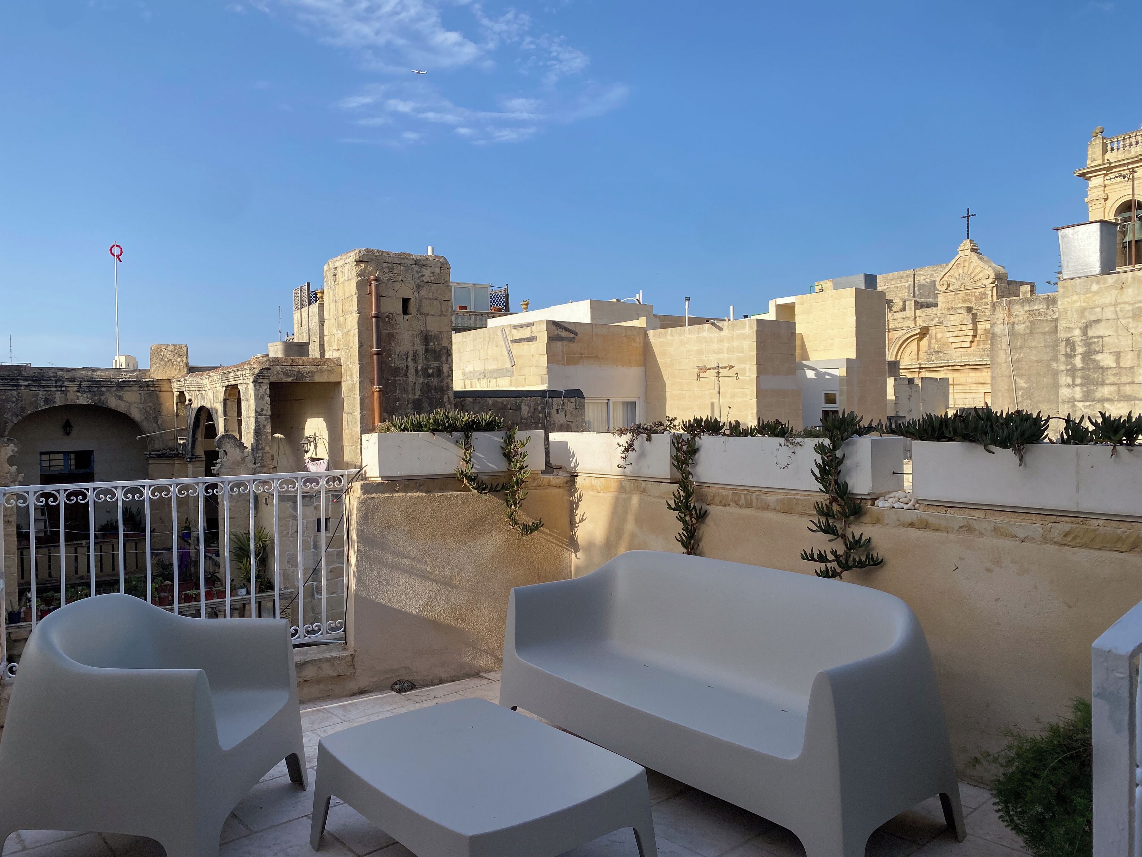 Une terrasse avec des places assises extérieures, une vue sur des bâtiments historiques et un ciel dégagé.