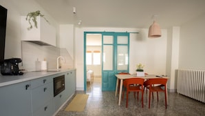 A modern kitchen with a built-in microwave, a coffee machine, and a sink. There is a dining area with a table and chairs, and a large window with a view.