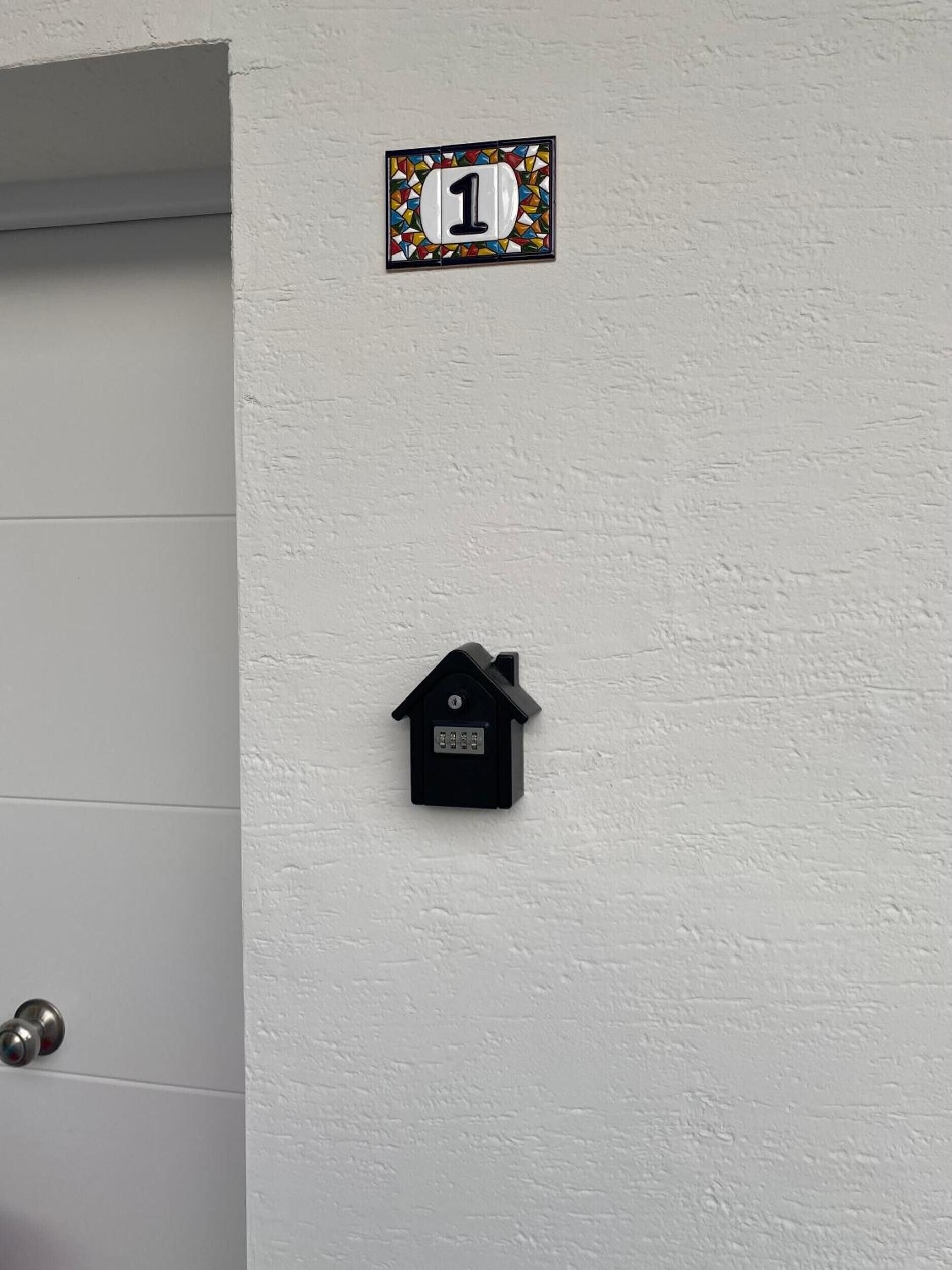 A door with a number plate marked '1' and a black intercom mounted on the wall.