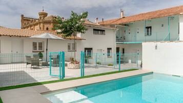 Una propiedad residencial con piscina, un patio cercado y una edificación tradicional con techo de tejas.