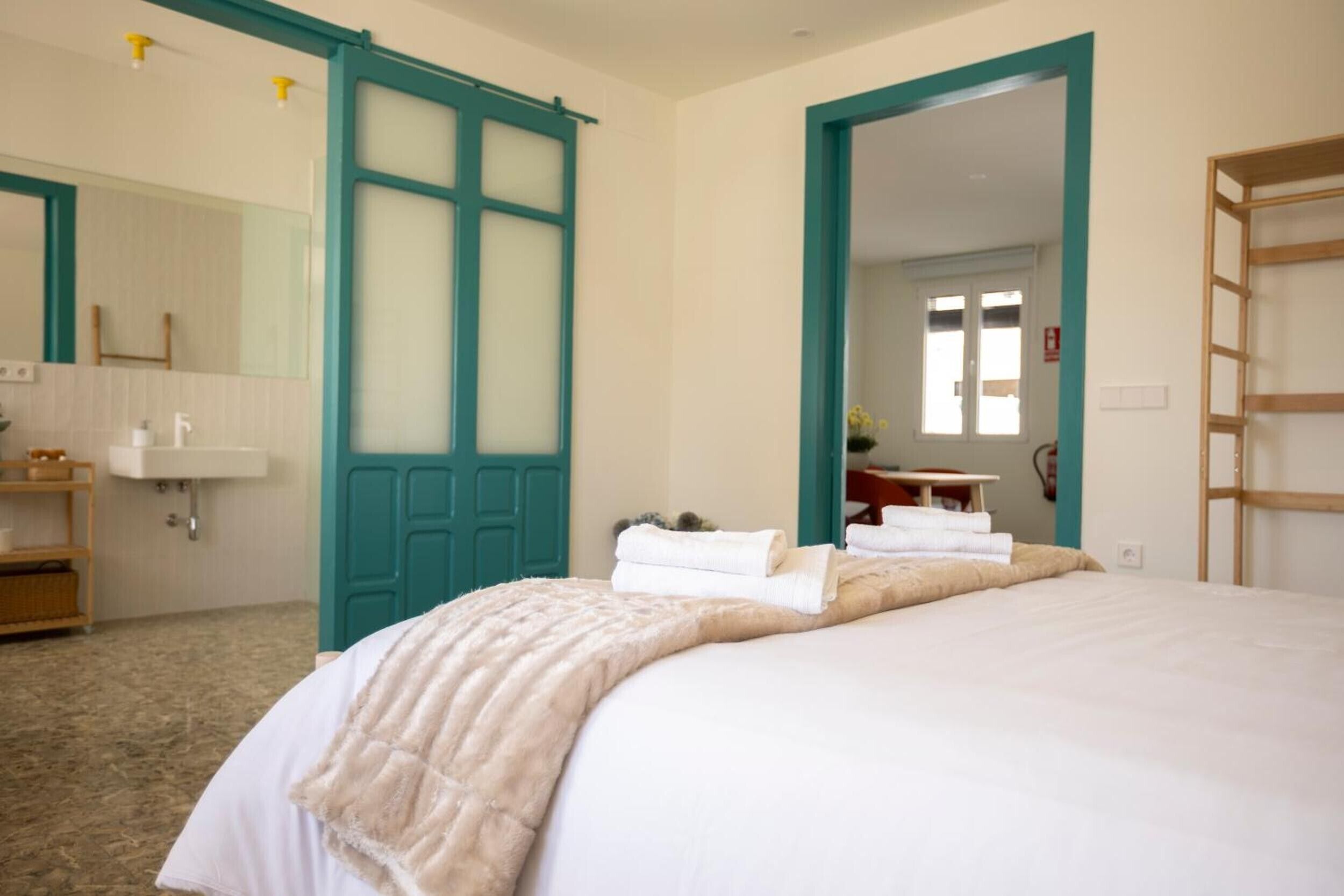 Una habitación de hotel con cama, baño con lavamanos y espejo.