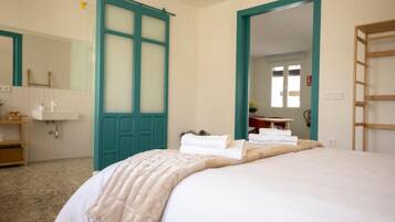 Una habitación de hotel con cama, baño con lavamanos y espejo.