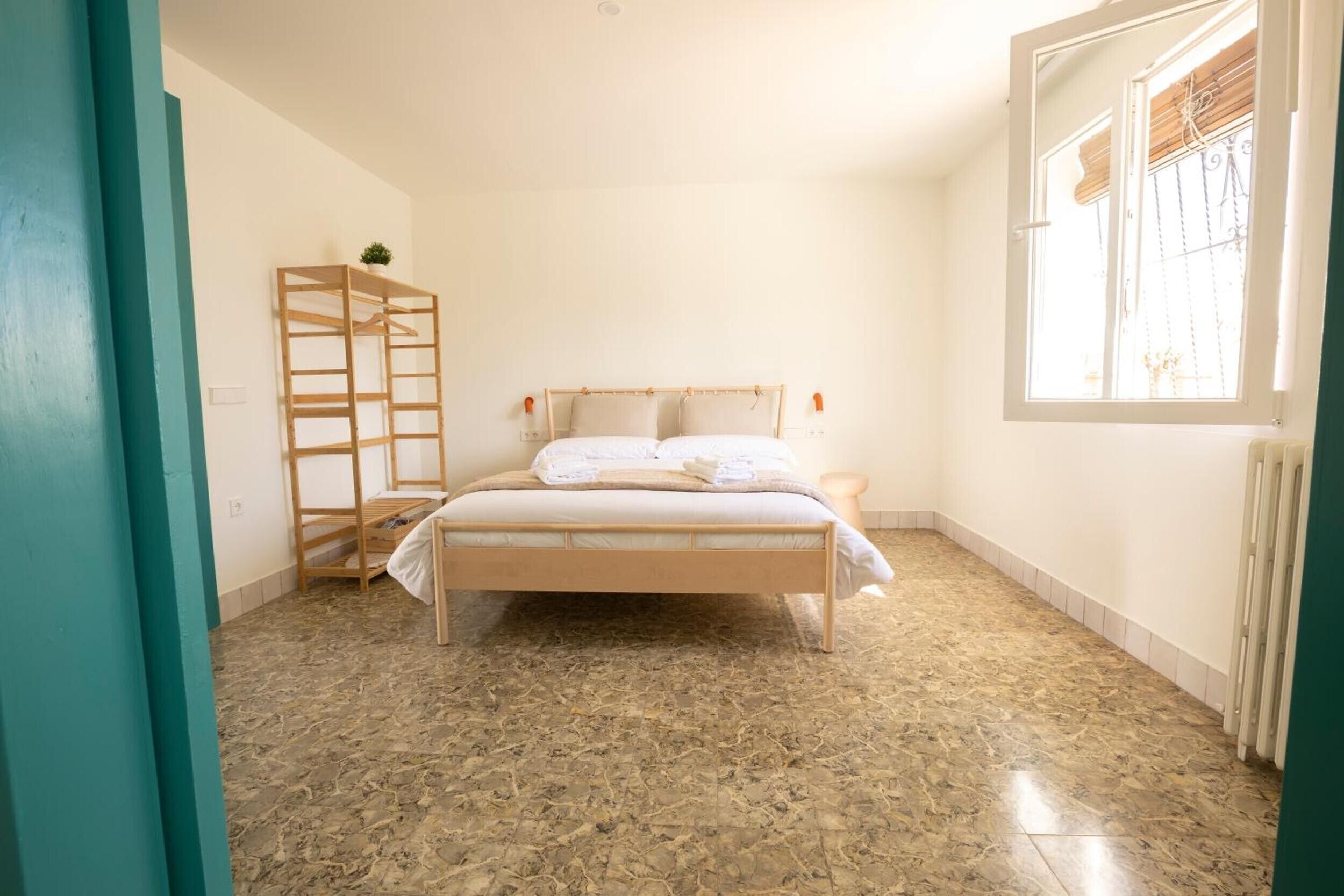 Une chambre à coucher avec un lit, une échelle en bois, une fenêtre donnant sur un paysage et un radiateur.