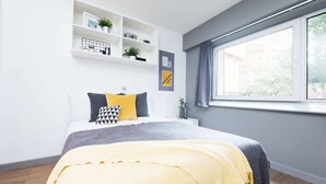A modern bedroom with a bed, bedside tables, a window, and built-in shelving.