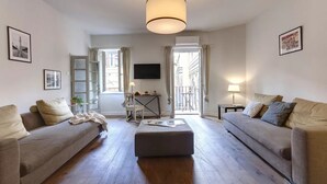 A living room with two sofas, a coffee table, a TV, and a staircase leading to an outdoor area. - Elegant Apartment with Terrace & Vasari Corridor Views in the Heart of Florence (Firenze)