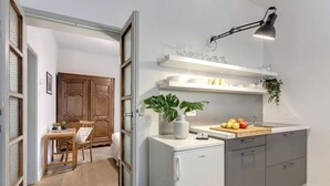 A compact kitchen with a refrigerator, a sink, and a countertop with fruits and a plant. - Elegant Apartment with Terrace & Vasari Corridor Views in the Heart of Florence (Firenze)