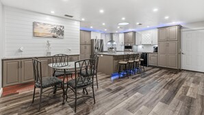 Una cocina moderna con una isla central, suelo de madera e iluminación colgante.