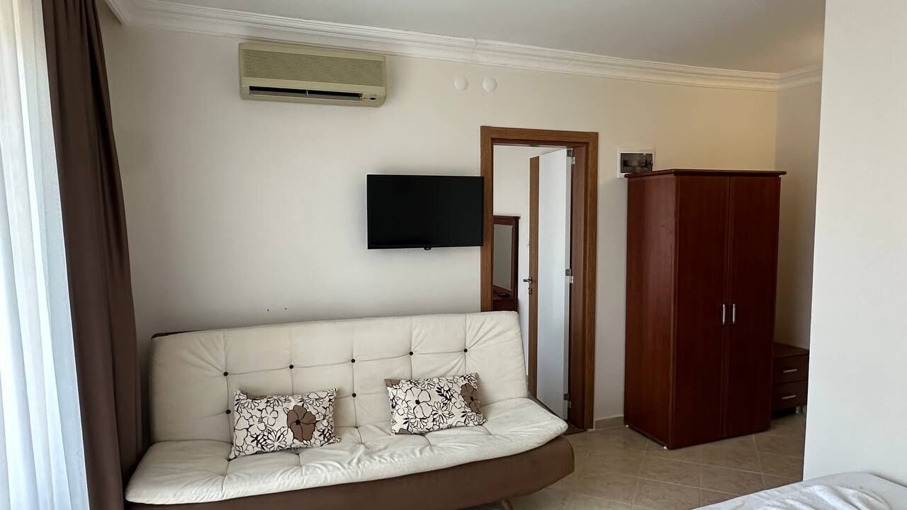 Une pièce comprenant un canapé, un téléviseur, une armoire et une porte.