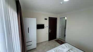 A hotel room with a bed, a wardrobe, a television, and a door leading to a bathroom.