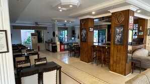 A restaurant with wooden bar counters, a kitchen in the background, and a seating area with tables and chairs.