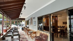 An outdoor café with tables and chairs, a covered seating area, and a view of the street.