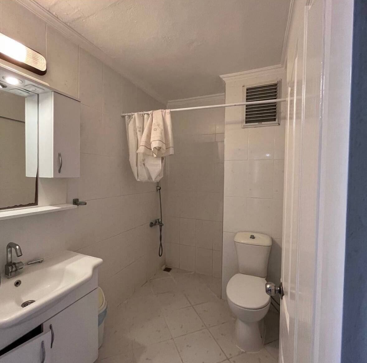 A small bathroom with a toilet, sink, and shower.