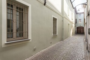 Un estrecho callejón adoquinado flanqueado por edificios, con amplias ventanas de rejas y una puerta al final.
