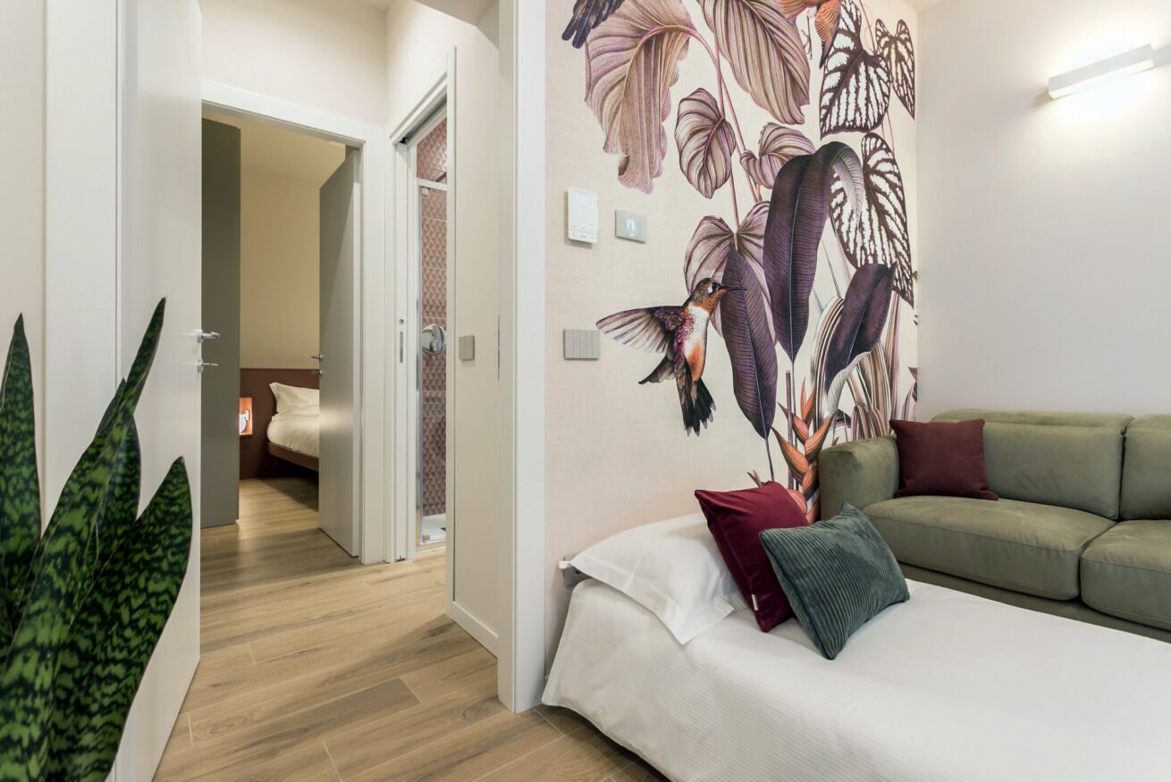 Ein modernes Interieur mit einem Bett, einem grünen Sofa und einer Wand mit einem großen Blumenwandbild.