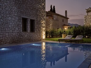 A stone building with a pool, lounge chairs, and a well-maintained garden. - Avesta Private Villas Iokasti (Lefkada)
