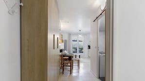 A hallway leading to a dining area with a table and chairs, a ceiling fan, and a view through a glass door to an outdoor area.