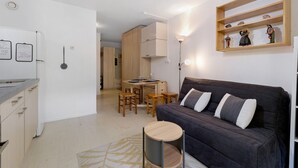 A compact living space with a kitchenette, a dining area, and a sofa.