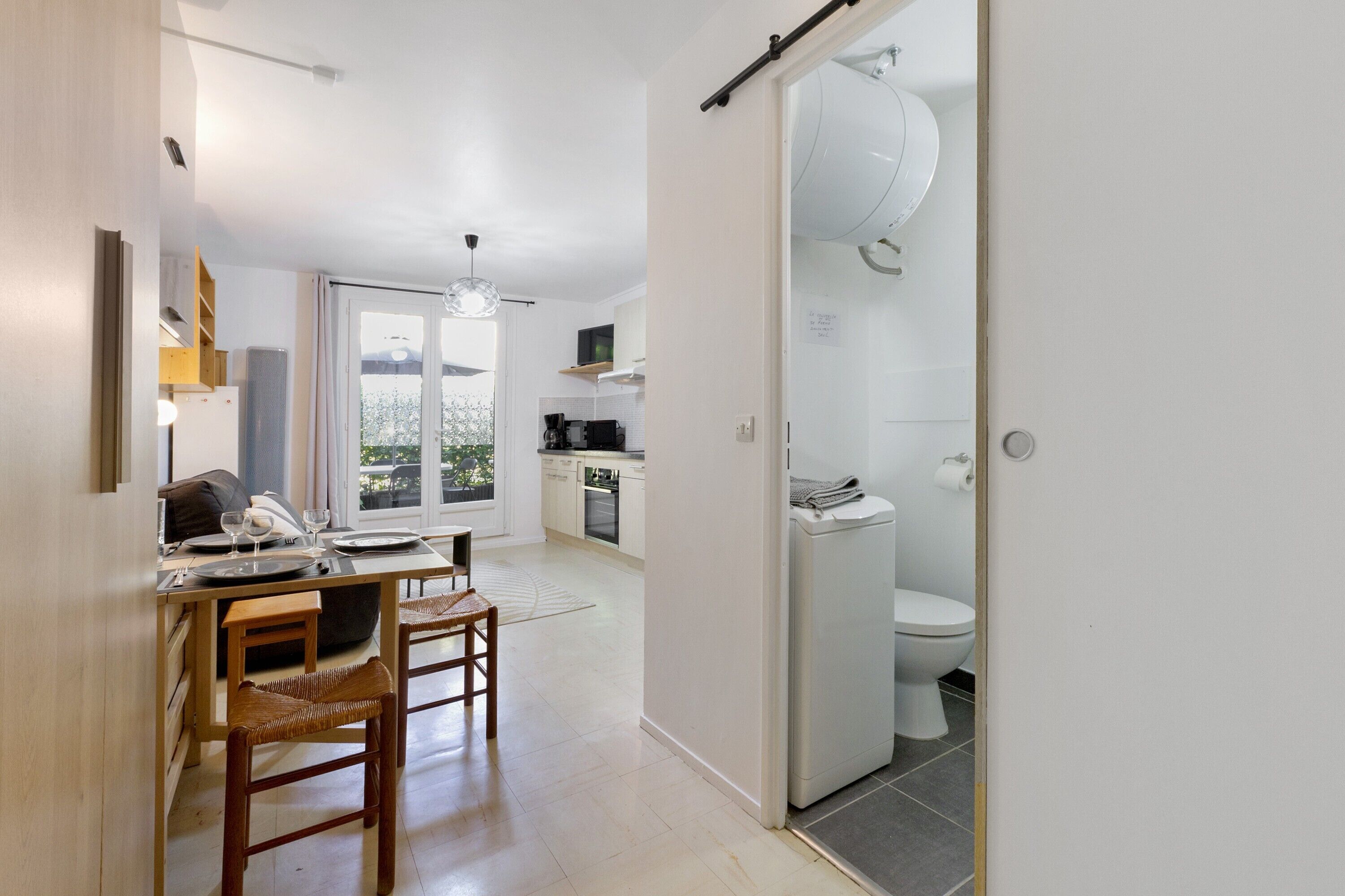 Une cuisine moderne avec un coin repas, un four encastré et une vue à travers la porte.