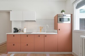 Una cocina moderna con armarios blancos, horno de acero inoxidable y ventana con persianas.