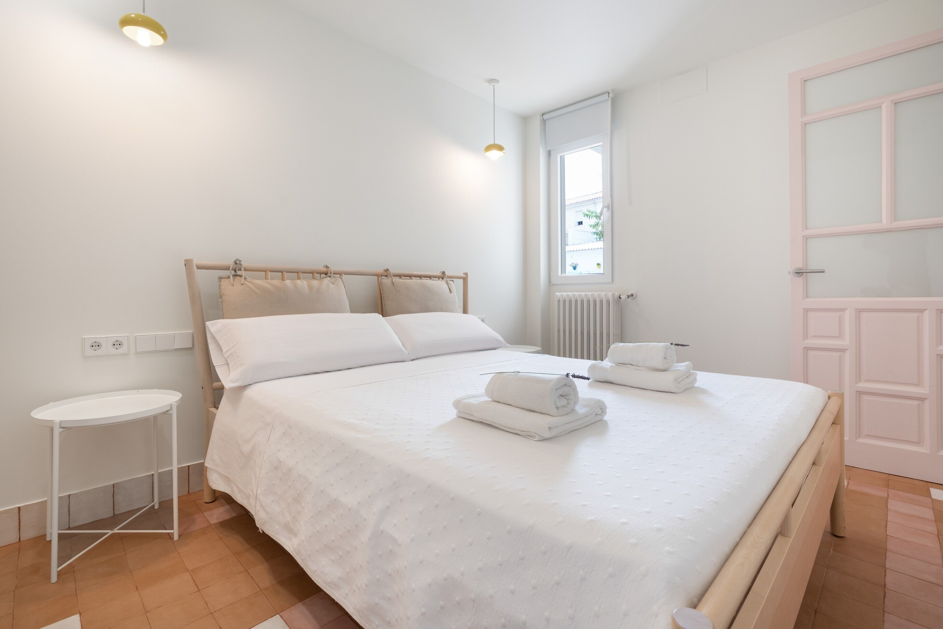 A bedroom with a bed, bedside table, and a window.