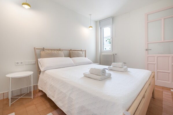 Un dormitorio con cama, mesita de noche y ventana.