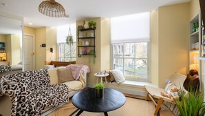 A cozy living room with a sofa, a chair, a round table, and a bookshelf.