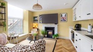 A living room with a fireplace, a television, a sofa, and a dining area.
