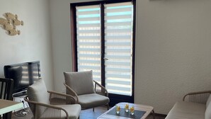 Uma sala de estar com sofá, cadeiras, mesa de centro e televisão.