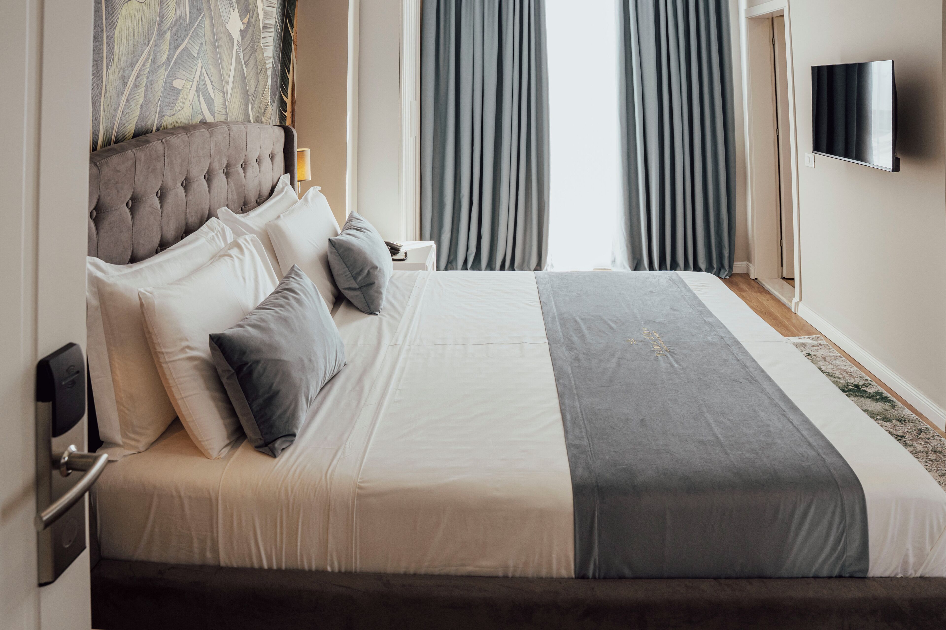 A modern hotel room with a large bed, a flat-screen TV, and a view of the outdoors.