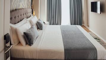 A modern hotel room with a large bed, a flat-screen TV, and a view of the outdoors.