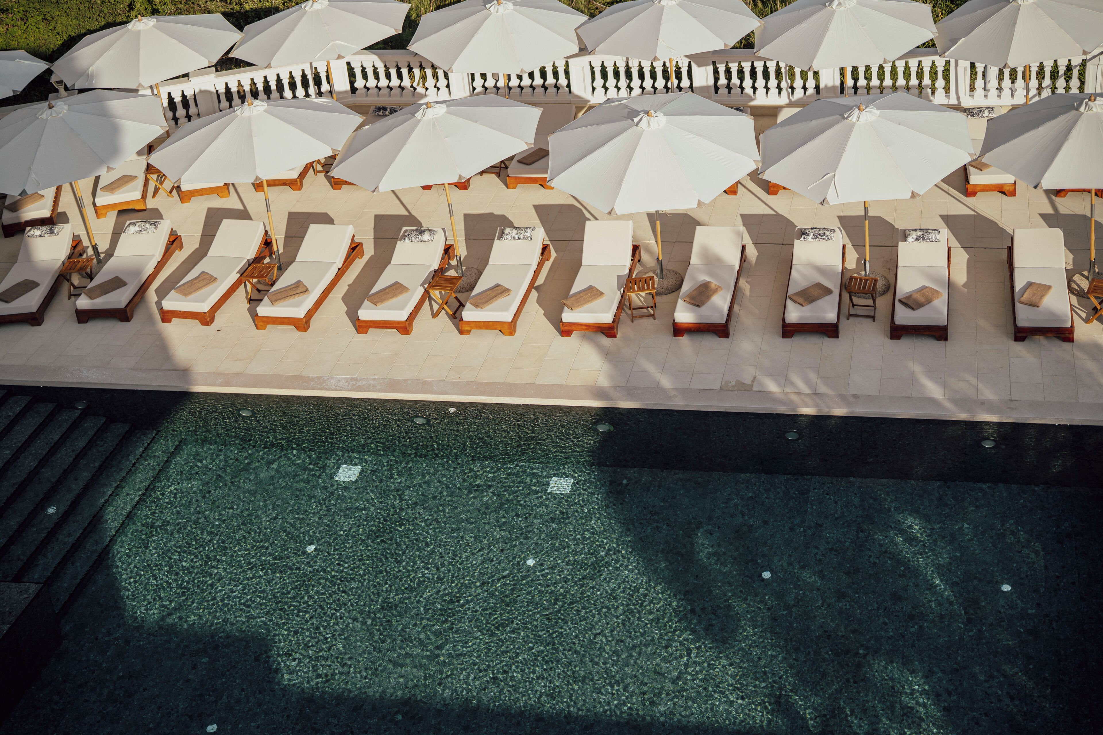 A poolside area with multiple sun loungers and umbrellas.