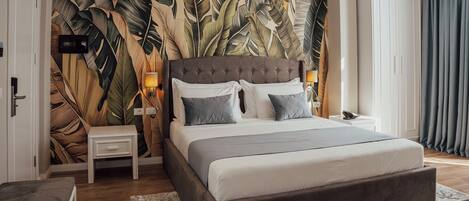 A bedroom with a large bed, a nightstand, a wardrobe, and a wall with a leaf pattern.