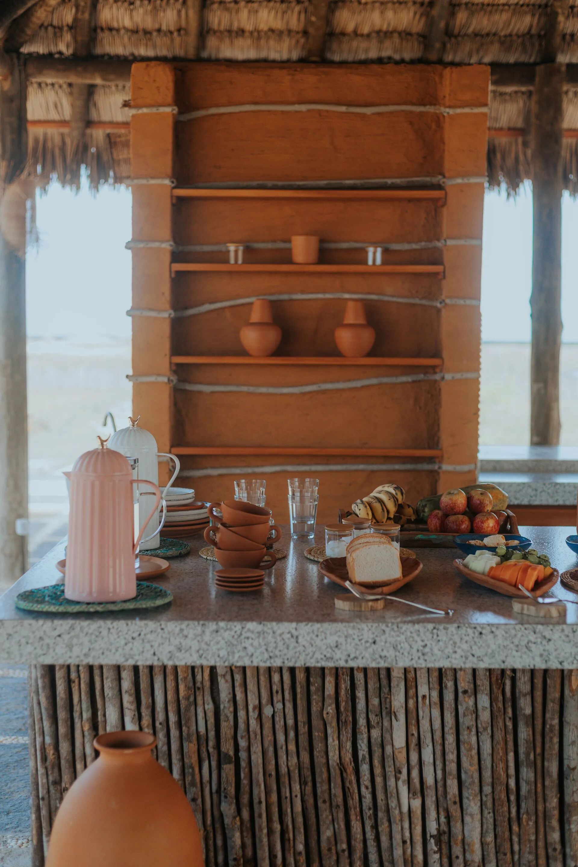 Un rincón de cocina rústico con estantes que exhiben cerámica, una cafetera y un frutero.