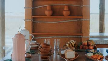 Un rincón de cocina rústico con estantes que exhiben cerámica, una cafetera y un frutero.