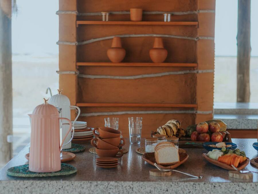 Un rincón de cocina rústico con estantes que exhiben cerámica, una cafetera y un frutero.