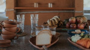 A rustic kitchen with terracotta pots, glasses, bread, and fruits on the counter. - Vila Ronquinha (Tutóia)