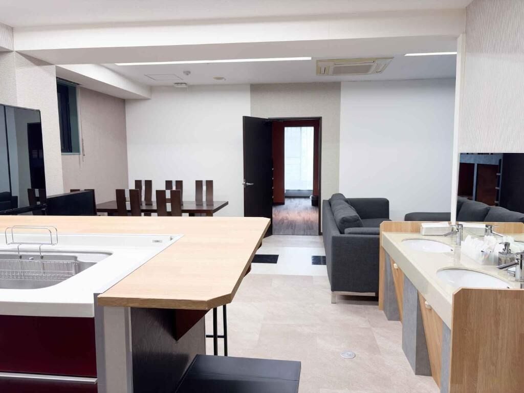 Una cocina moderna con una isla central, un comedor con sillas, un sofá y un ventanal grande.