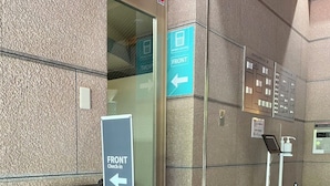 A hotel entrance with a check-in desk, a payment machine, and directional signs.