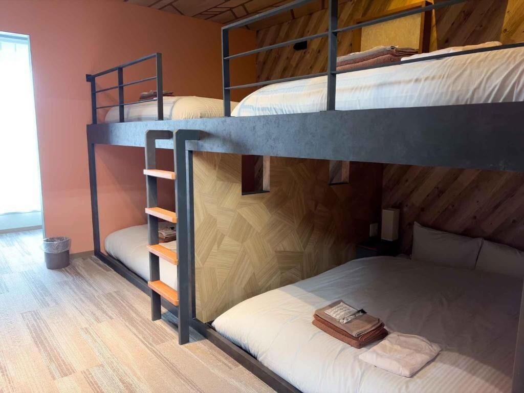 Habitación con literas, techo de madera y una ventana.