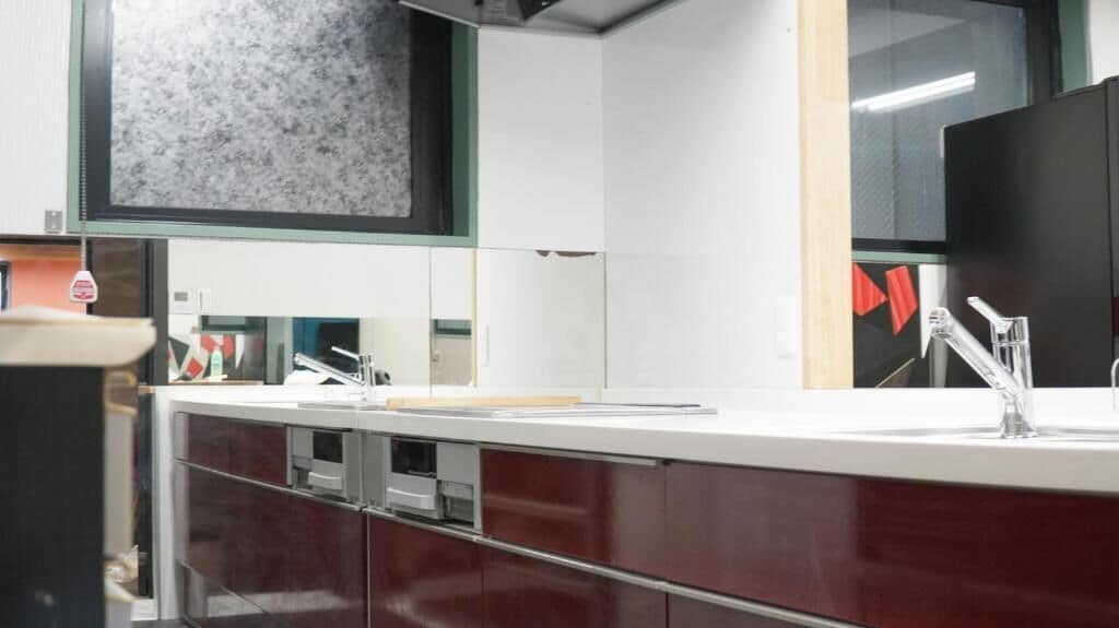 Una cocina moderna con encimera blanca, grifo de acero inoxidable y salpicadero de mármol.