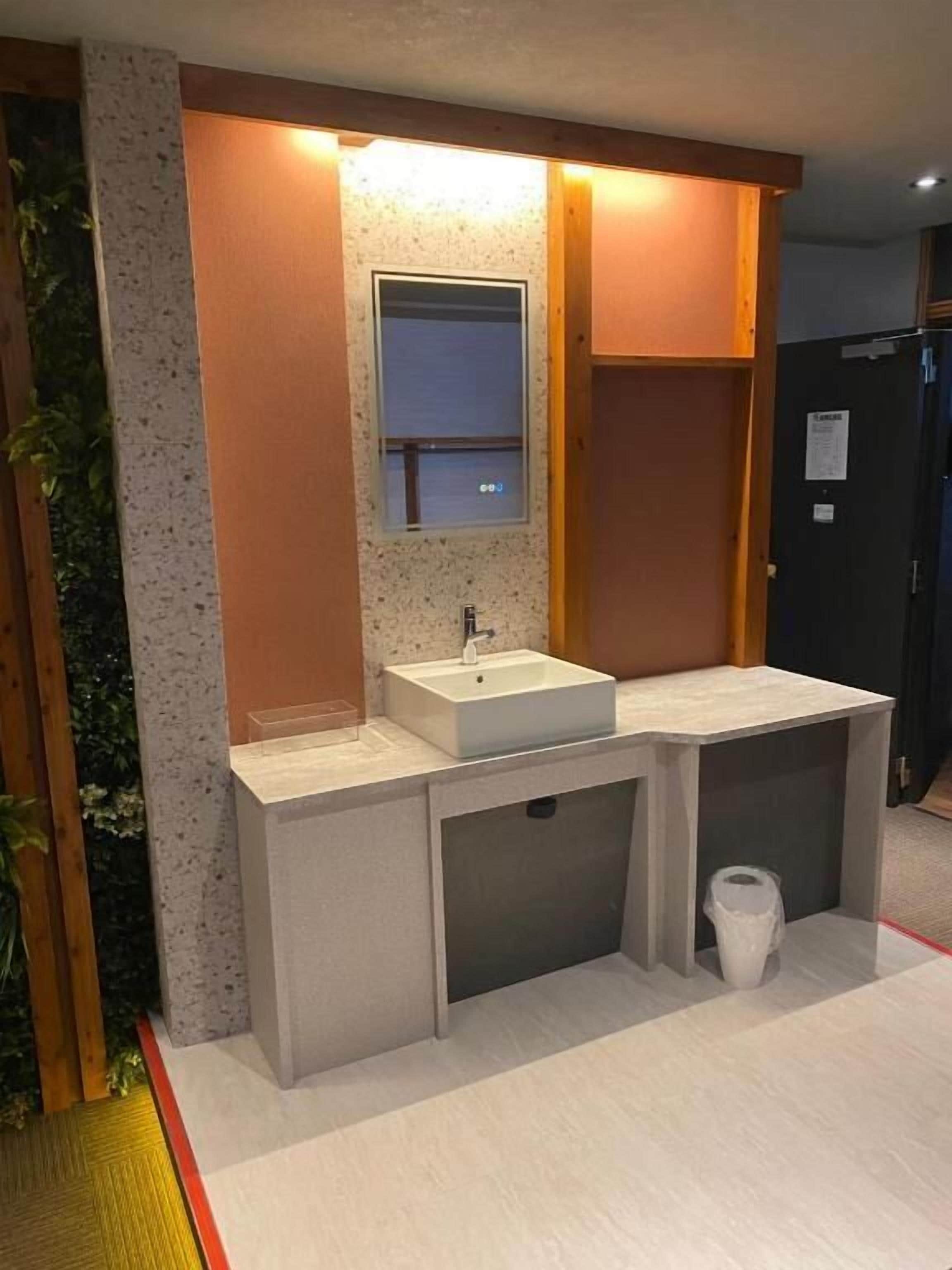 Et badeværelse med vask, spejl og toilet.