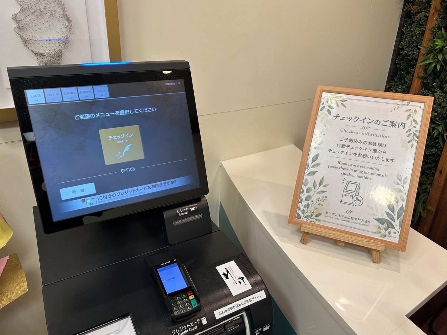 A check-in kiosk with a digital screen, a credit card reader, and a receipt printer.