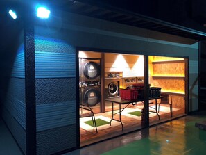 Un cuarto de lavandería compacto con varias lavadoras, una zona de estar y una mesita.