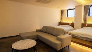 A modern hotel room with a sectional sofa, a round coffee table, and a bed.