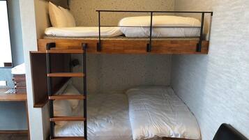 Una cama litera con escalera, un escritorio con lámpara y una silla en una habitación con paredes con motas.