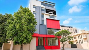 A modern townhouse with a red facade, large windows, and a sign indicating it is serviced by OYO. - Deluxe Room Ranipur Mor (Haridwar)