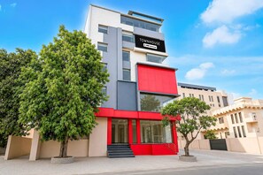 A modern townhouse with a red facade, large windows, and a sign indicating it is serviced by OYO. - Deluxe Room Ranipur Mor (Haridwar)
